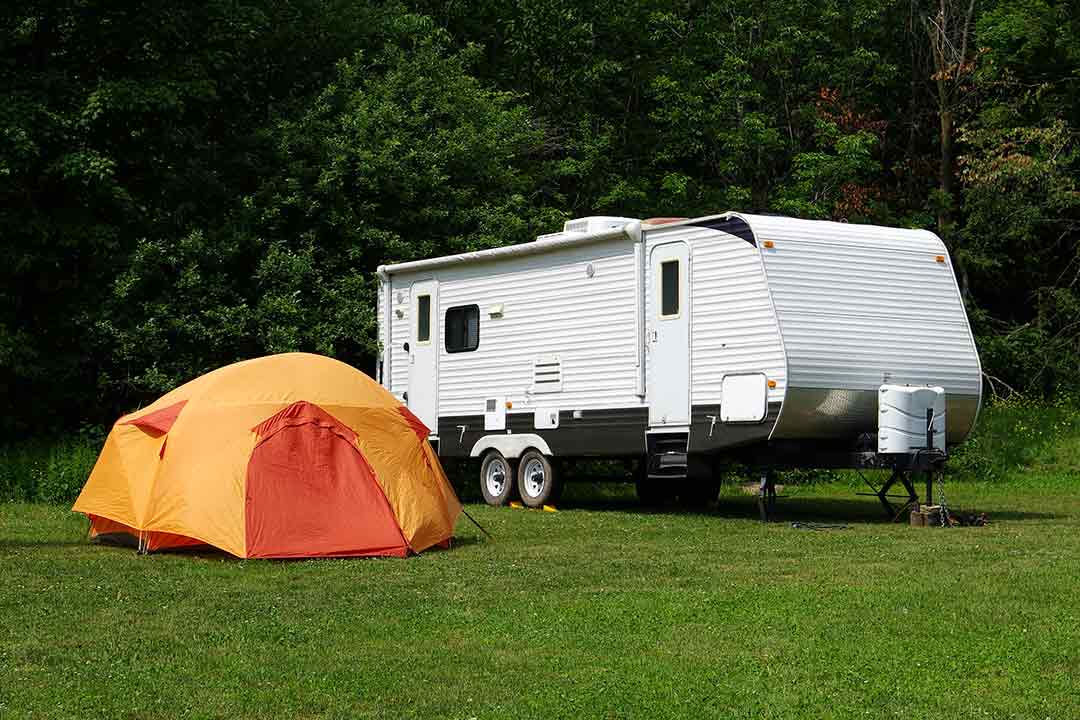 A travel trailer camping out with a yellow tent in front of it
