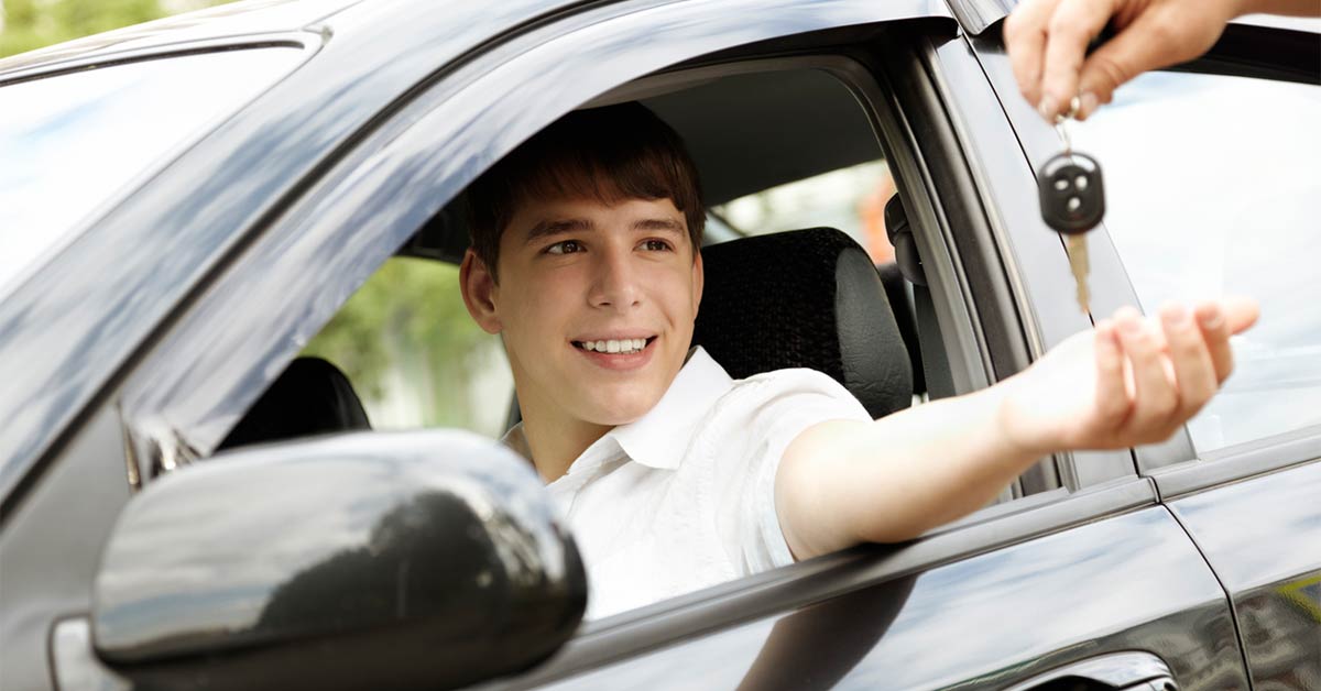 Image shows young man reaching for keys while sitting in a car.