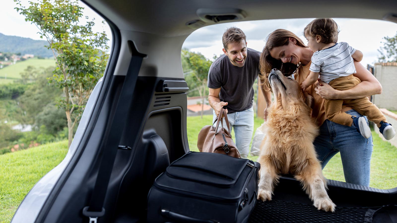 a happy family and their dog getting luggage from car