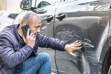 a person reviewing their car's damage after an accident