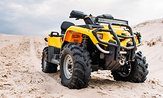 A yellow ATV off-roading in the sand