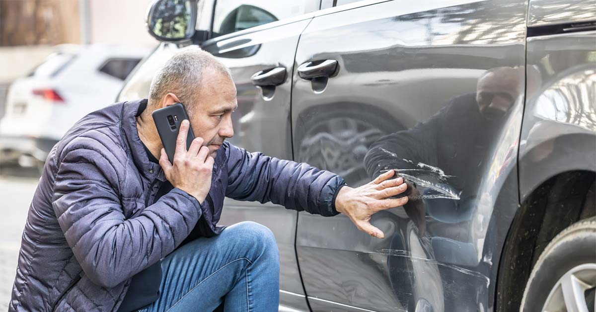 A person on the phone inspecting their car damage