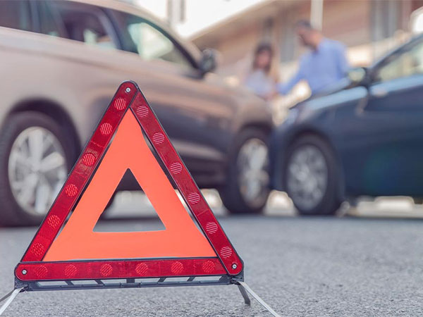 a hazard traffic triangle on the road in front of a car accident