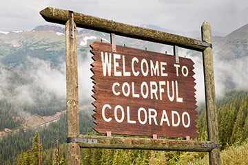 A wooden roadside that reads Welcome to Colorado