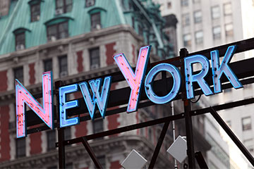 A sign that reads New York in blue and pink colors